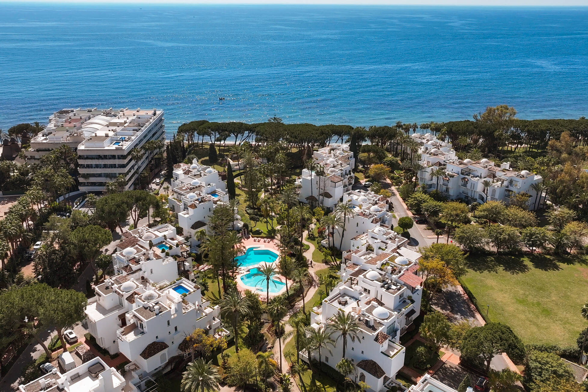 Aerial view of the gated Alhambra del Mar community, its lagoon pools and the Mediterranean beyond