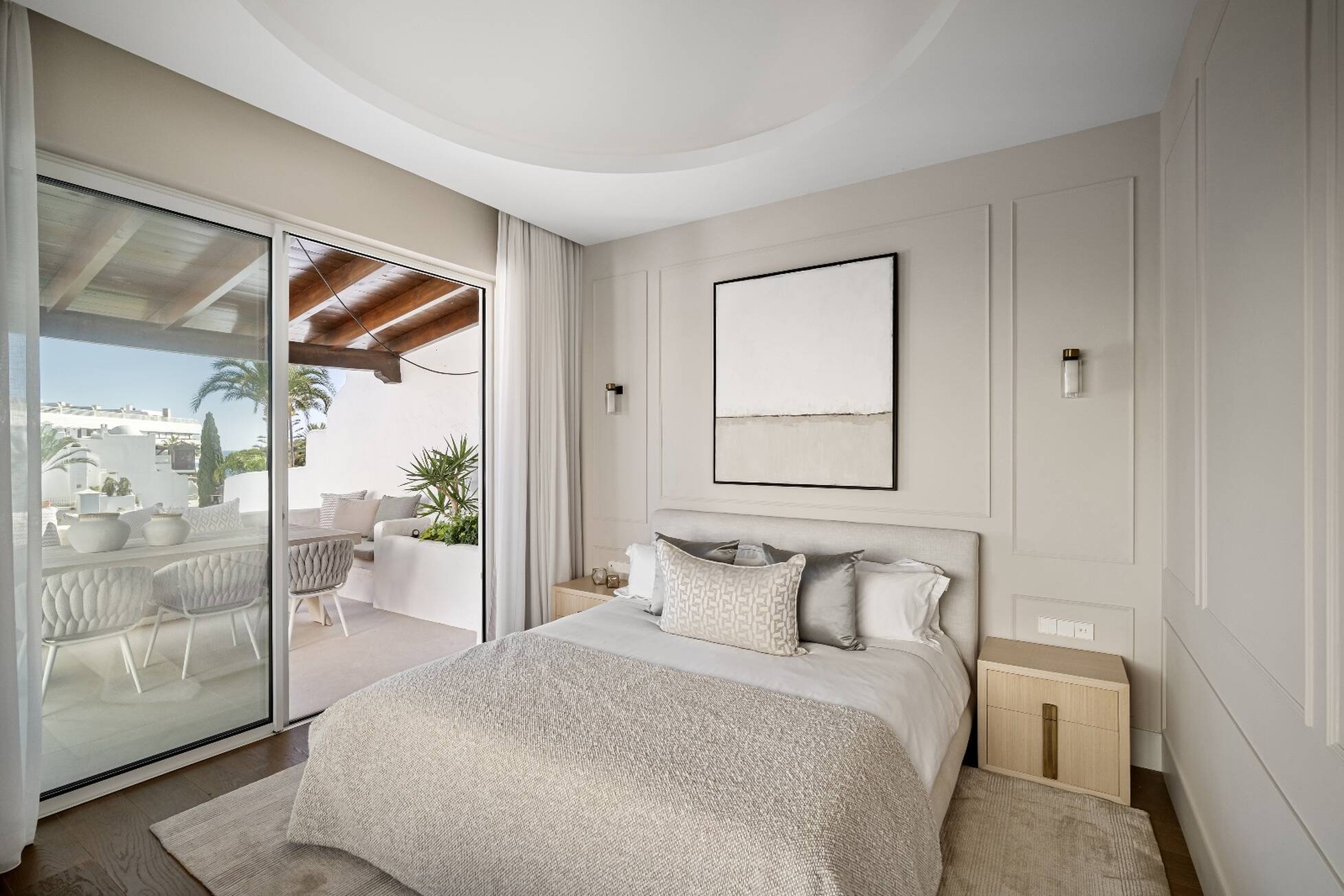 Guest bedroom with panelled walls and sliding doors to a private covered terrace