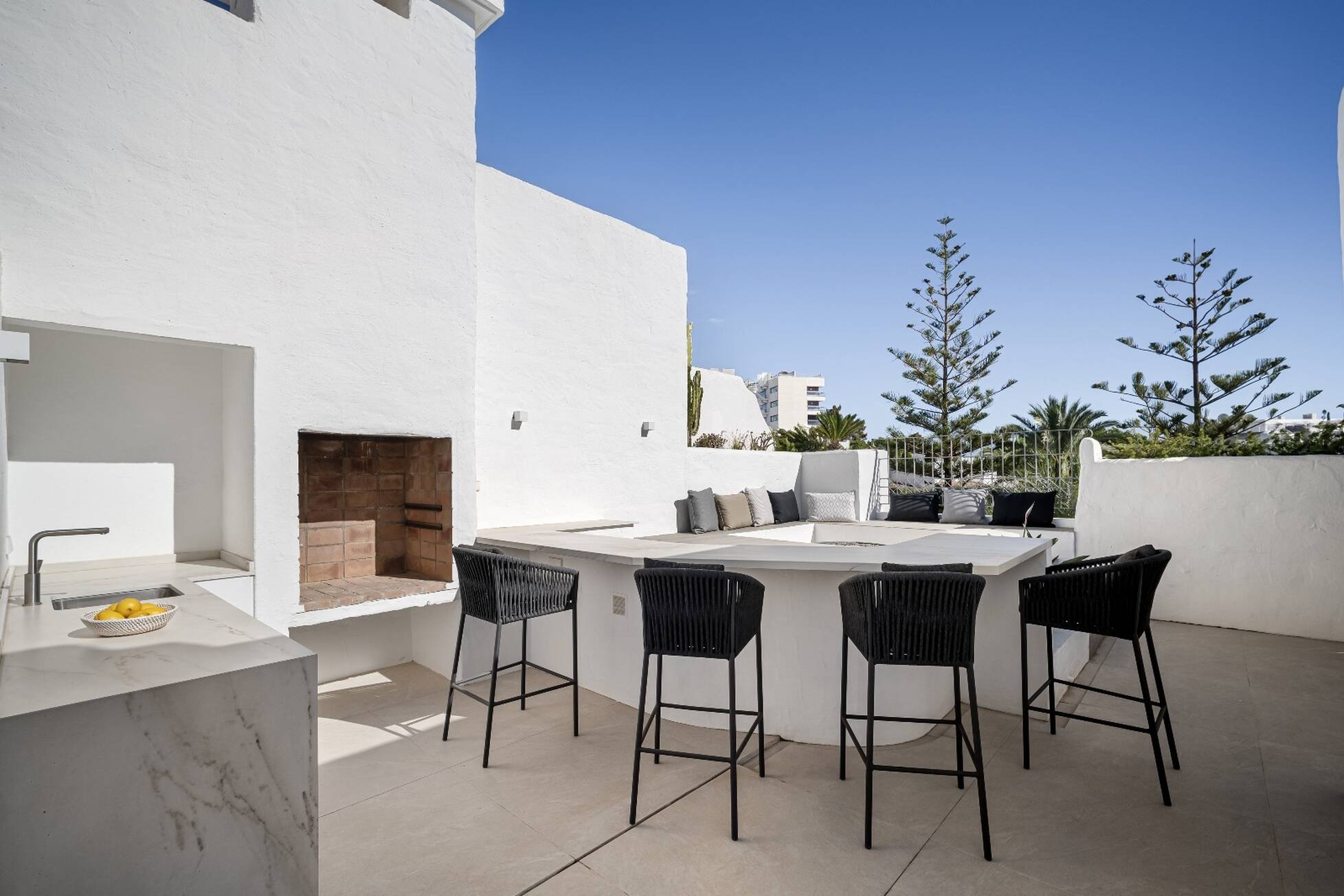 Rooftop outdoor kitchen with marble counter, wood-fired barbecue and bar seating