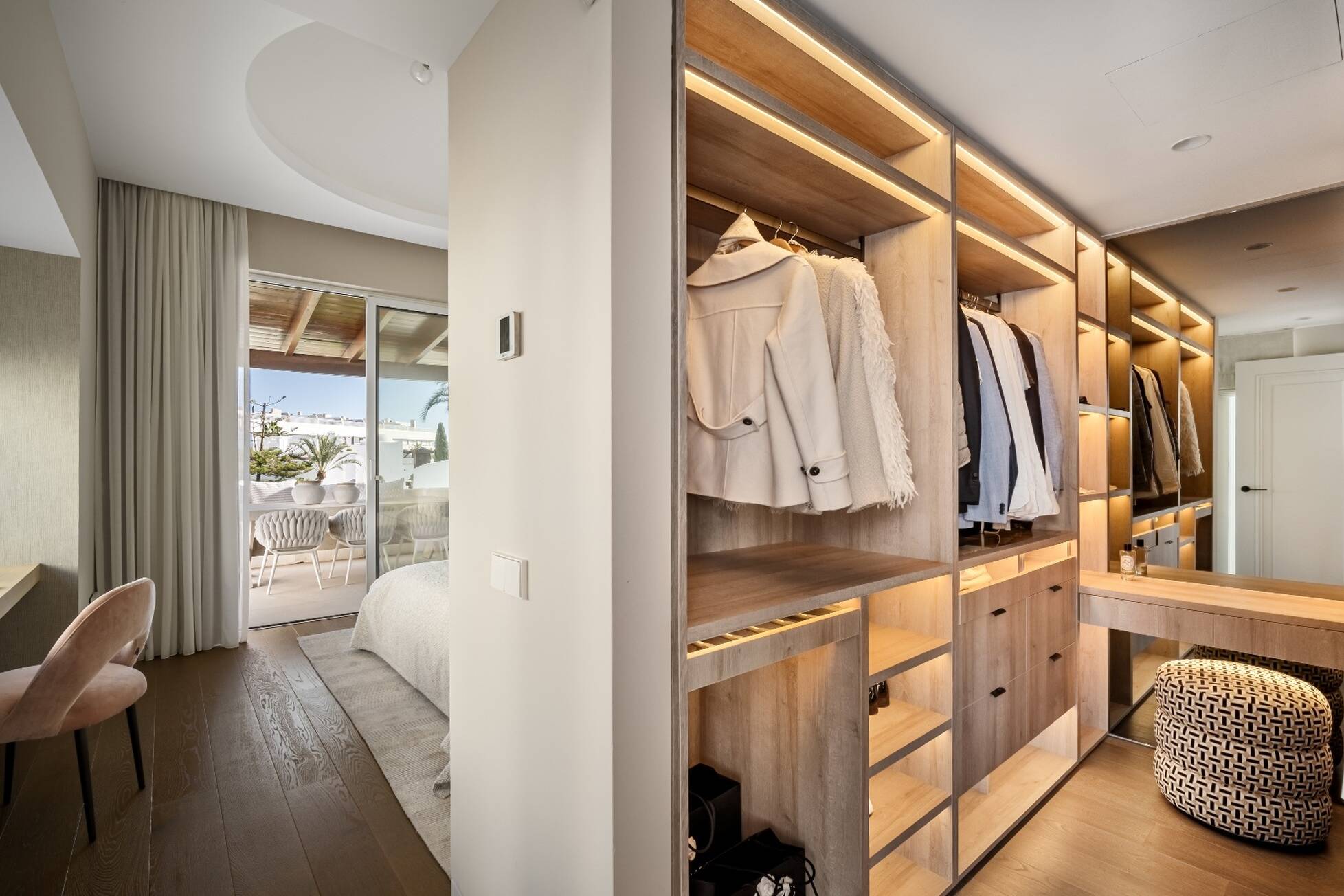 Illuminated oak walk-in wardrobe adjoining the master bedroom with terrace views