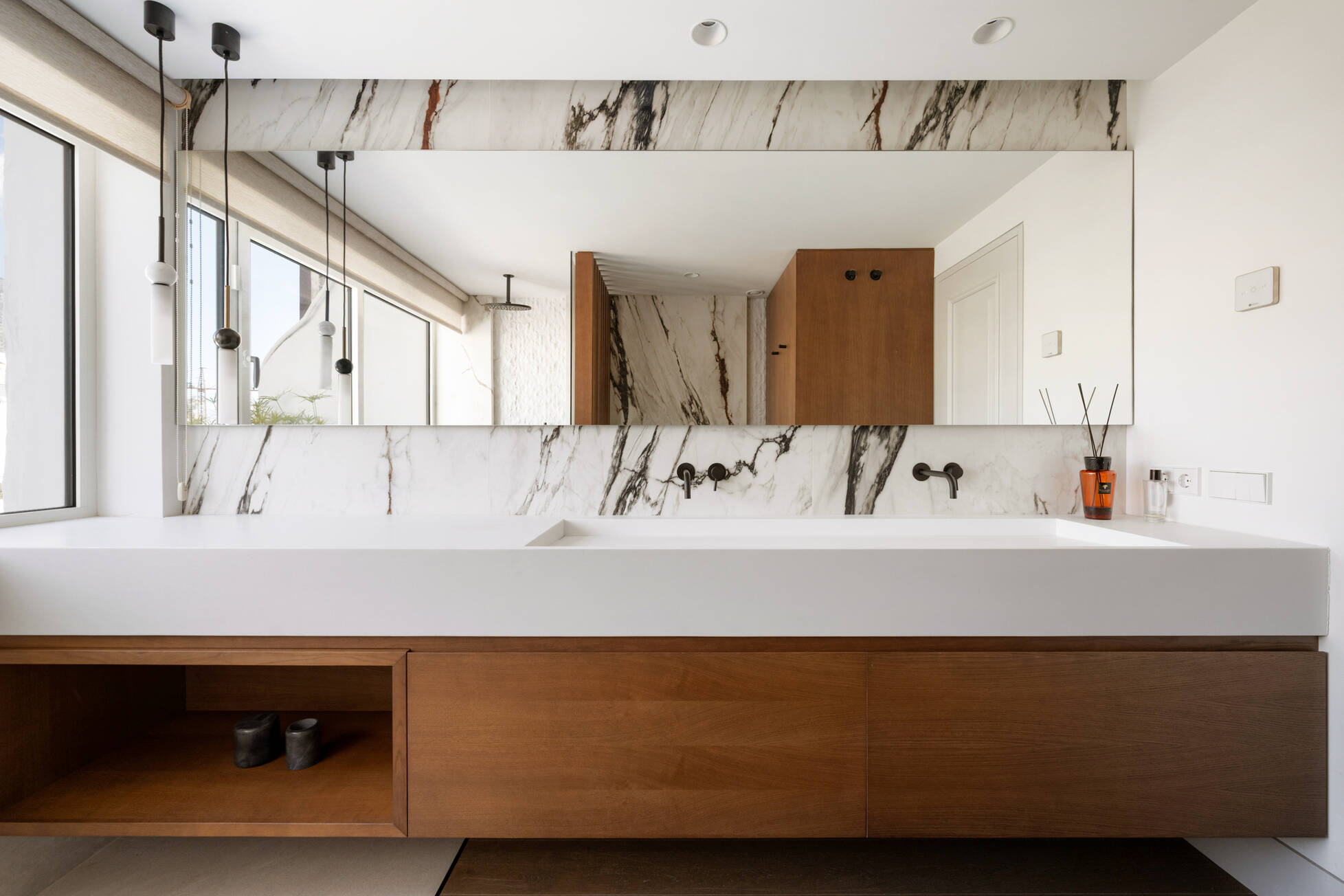 Master bathroom with book-matched marble, floating walnut vanity and full-width mirror