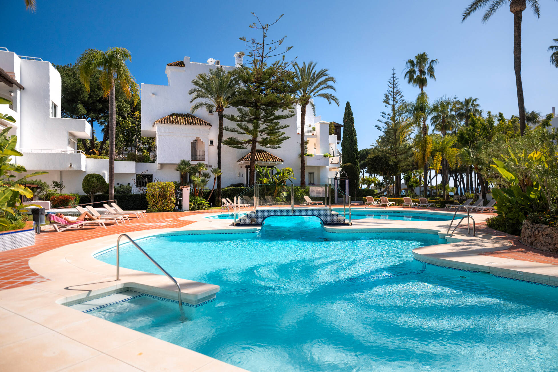 Communal pools of Alhambra del Mar surrounded by whitewashed buildings and palms