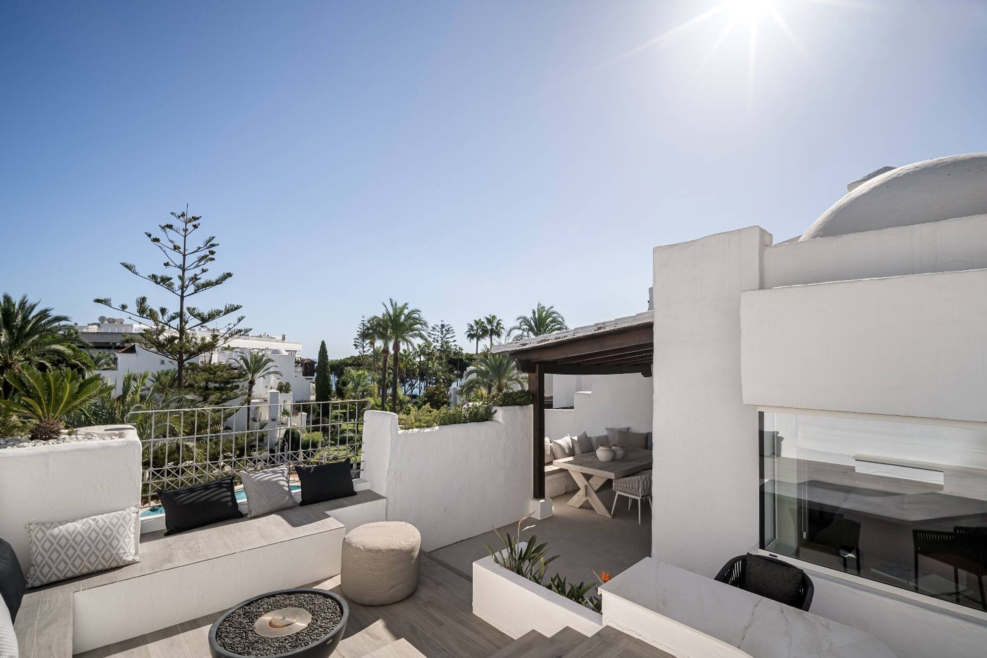 Rooftop solarium with built-in seating, fire bowl and a pergola-shaded dining area