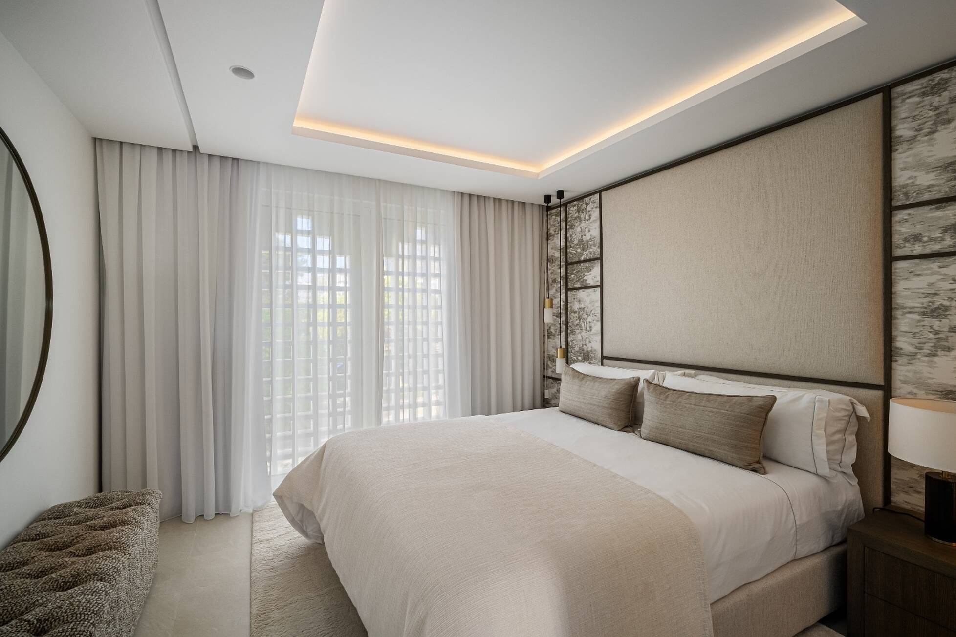 Master bedroom with upholstered headboard, sheer curtains and a coved lit ceiling