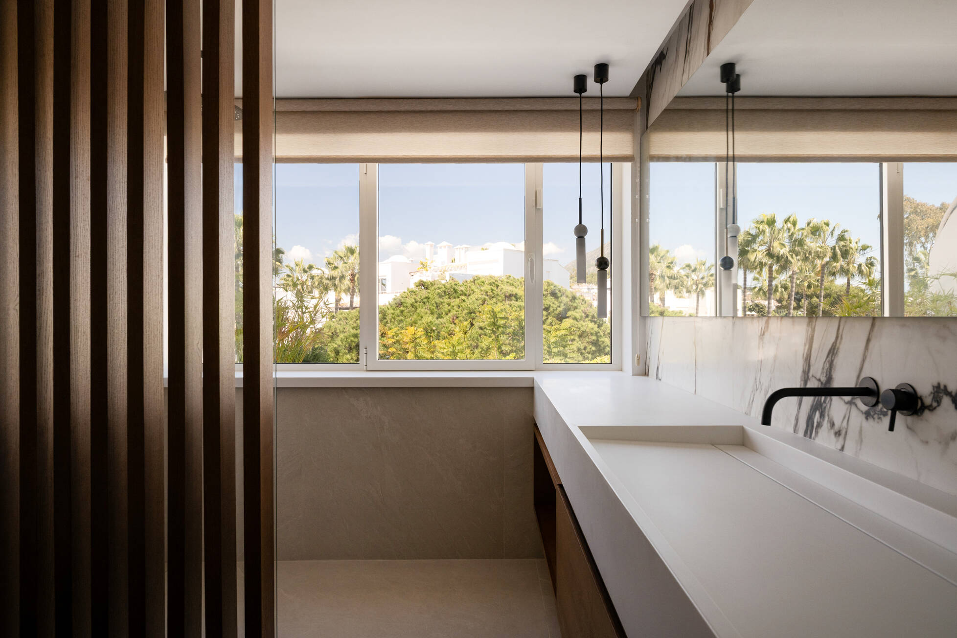Bathroom with a long stone trough basin, oak screen and windows over the treetops