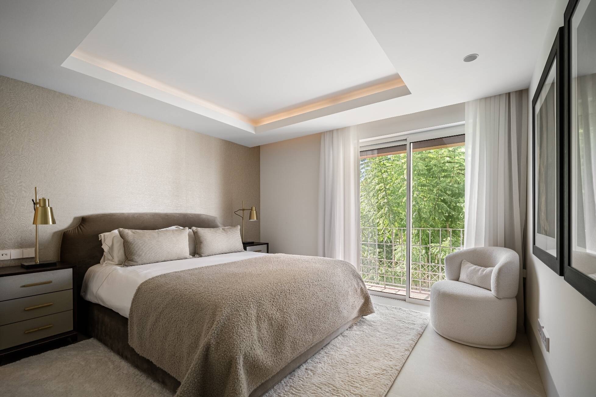 Second bedroom with velvet bed, brass reading lamps and doors to a green balcony