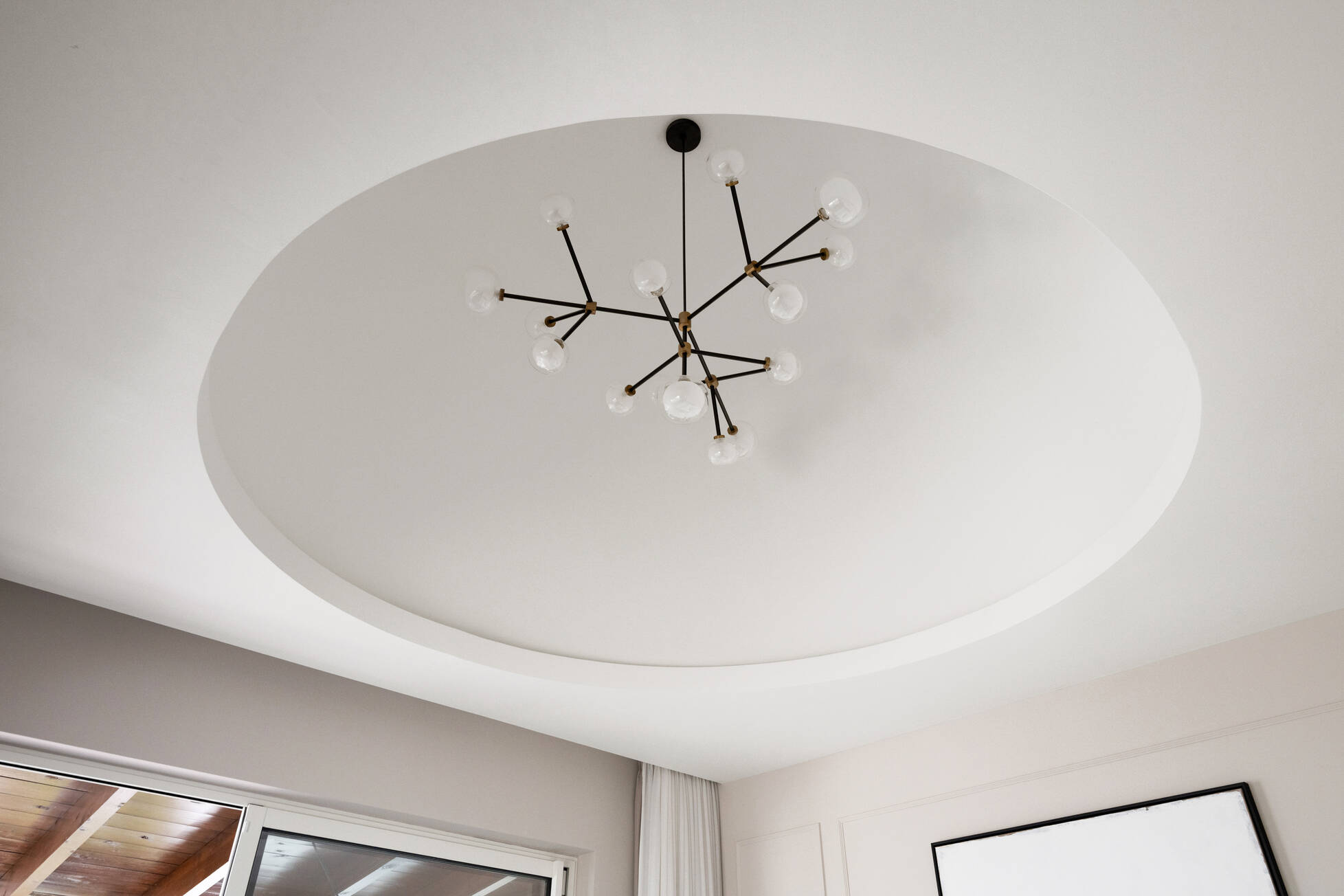 Circular recessed ceiling detail with a brass and glass constellation chandelier