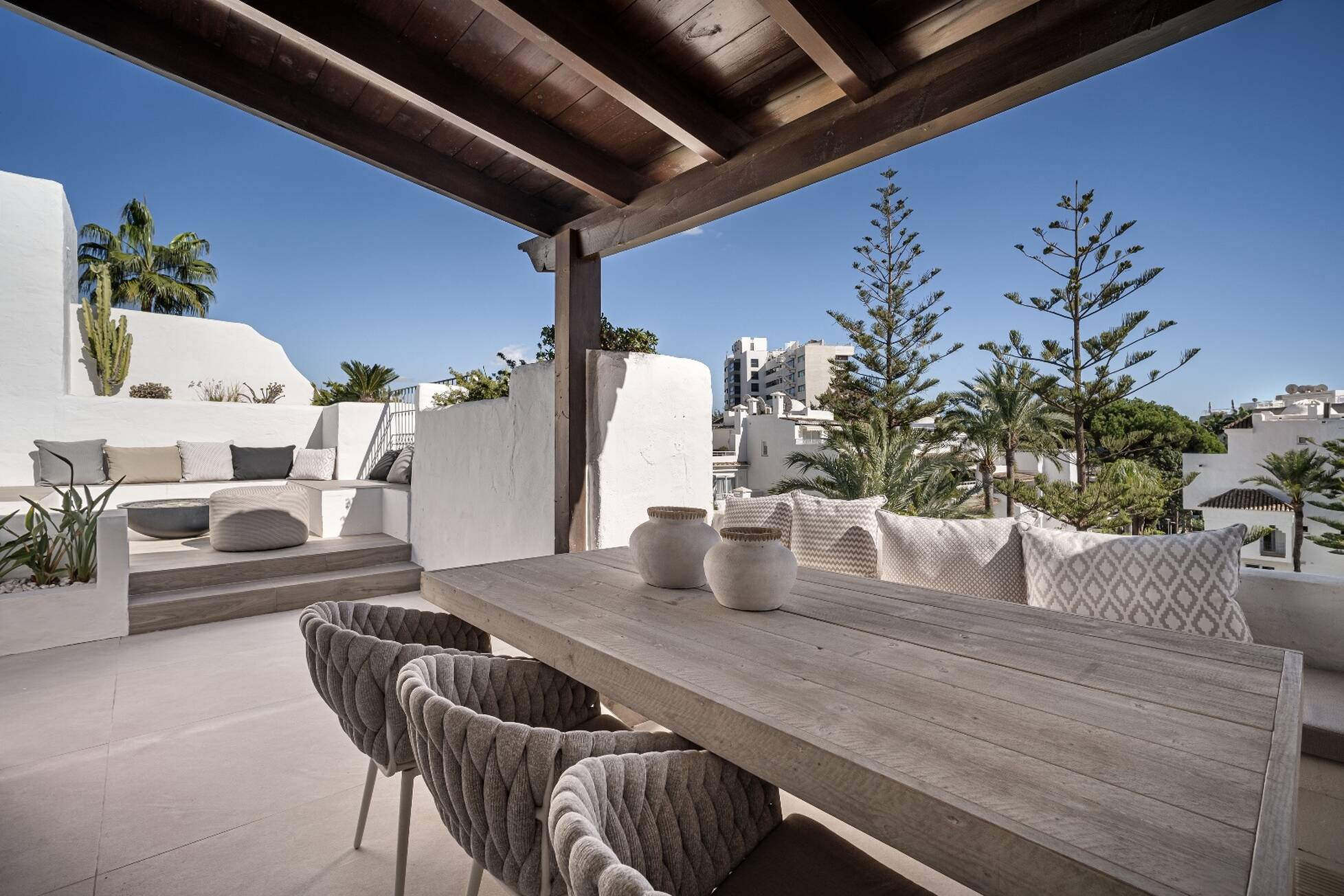 Pergola-shaded rooftop dining table for eight looking over palms and rooftops